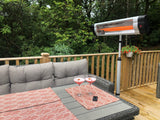 Load image into Gallery viewer, KMH-2500R 2.5KW Free Standing Infrared Heater on a wooden patio next to a grey outdoor corner sofa and wicker grey table