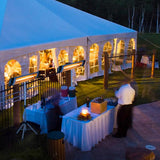 Load image into Gallery viewer, Socialising area at night with a large white gazebo and outside catering area with two white tables full of drinks and two KMH-3000R 3KW Free Standing Infrared Heaters